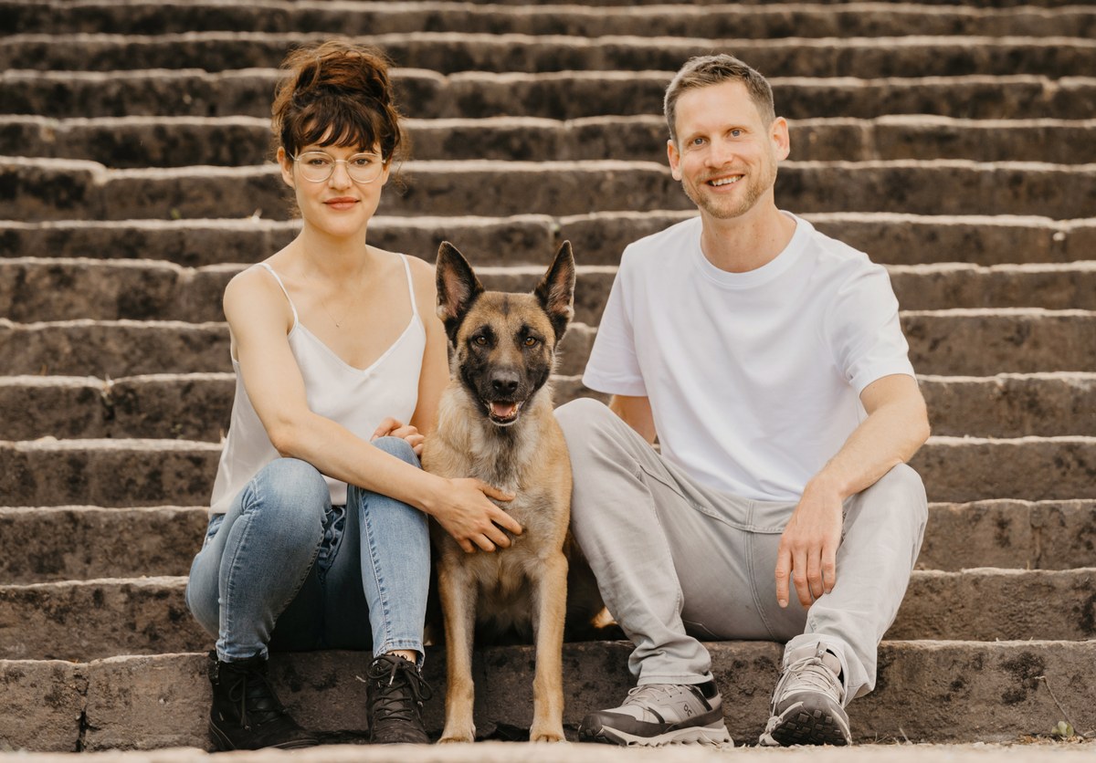 Ronja und Clemens sitzen mit ihrer belgischen Schaeferhuendin Mali auf einer Treppe